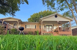 Ein zweistöckiges Haus mit überdachter Veranda und Grill im Vorgarten.