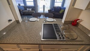 A kitchen with a built-in stove, a microwave, and a sink. There are two chairs and a dining table set up in the adjacent living area. - Lazy Days Lakefront Retreat Lake Granbury home, yard, dock-lift, covered parking (Granbury)