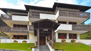 A multi-story building with balconies, a staircase leading to the entrance, and flower boxes on the ground level. - Lovely apartment for 2 guests with WIFI and TV (Ragoli)