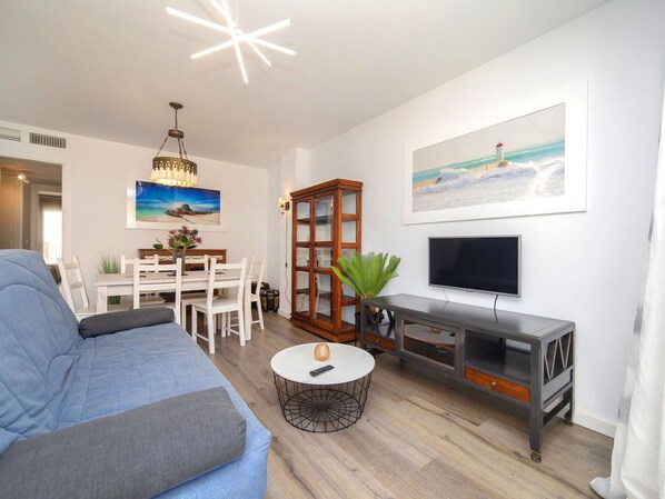 Relax in this stylish living room with a sofa, coffee table, TV, and dining area.