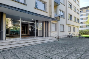 Un bâtiment moderne doté d’une entrée couverte, de marches menant à la porte et de vélos garés à l’extérieur.