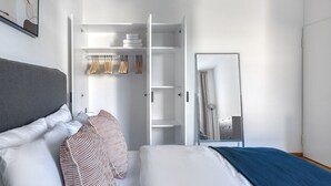 Un dormitorio con cama, armario y espejo.