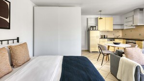 Une chambre d’hôtel moderne équipée d’un lit, d’une petite table à manger et d’une kitchenette.