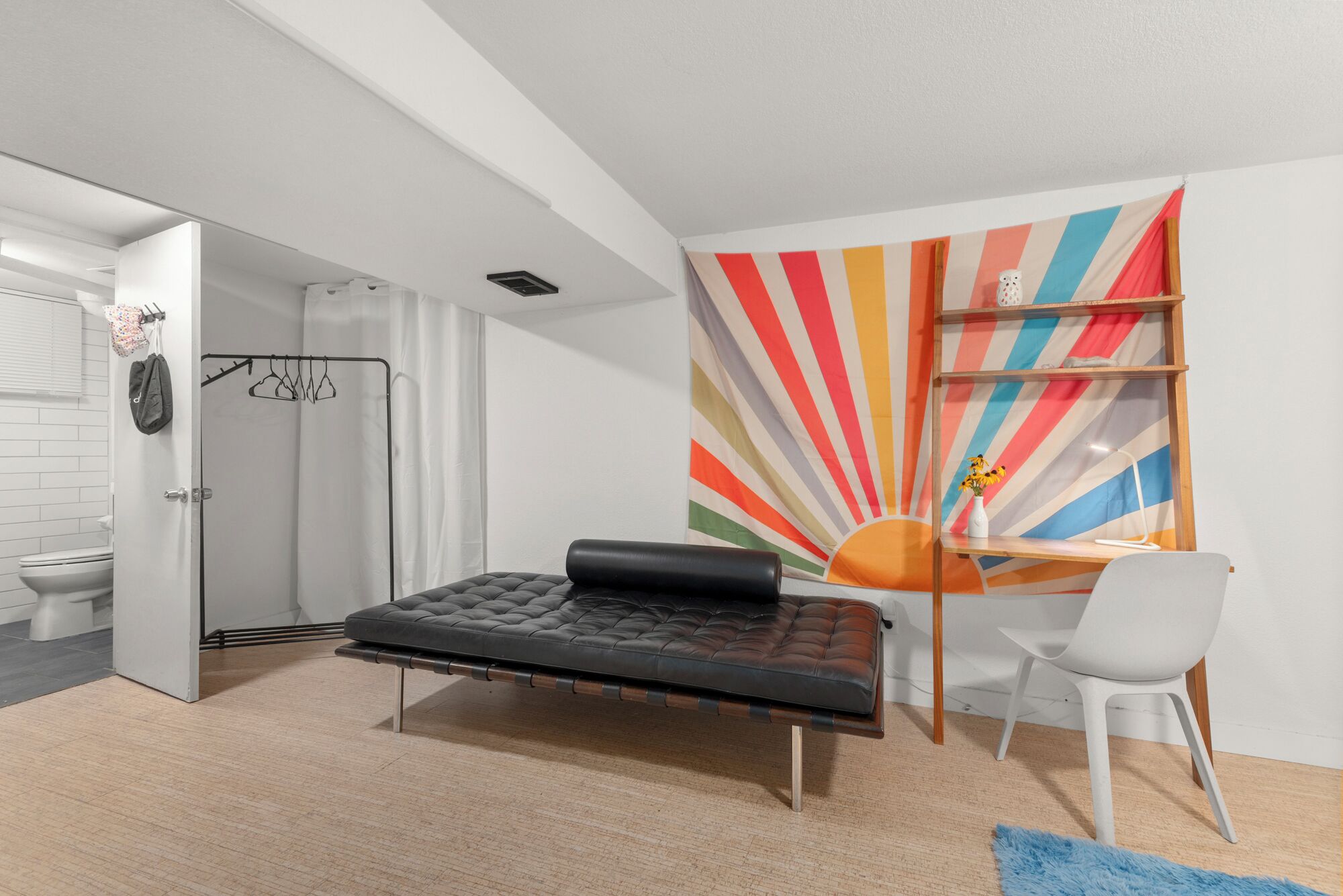A modern bedroom with a bed, a desk, and a colorful wall mural.
