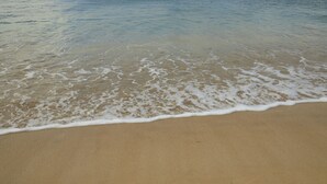 A beach with gentle waves lapping at the shore.