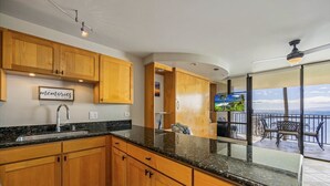 A kitchen with wooden cabinets, a granite countertop, and a view of a balcony with outdoor furniture.