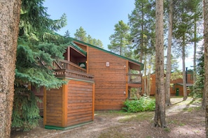 Guests can enjoy a balcony with a railing, surrounded by tall pine trees.
