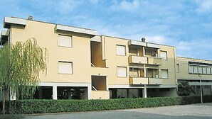 A multi-story building with a flat facade, balconies, and a parking area in front. - Cosy apartment for 6 guests with TV and balcony (Rosignano Marittimo)