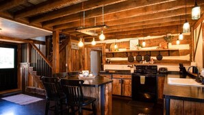 A rustic kitchen with wooden beams, a bar area with stools, and a stove.