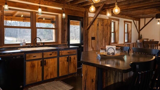 A rustic kitchen with wooden cabinets, a large island, and pendant lighting.