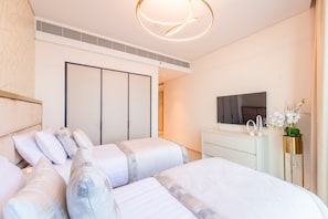 A modern bedroom with a large bed, a TV, and a dresser.