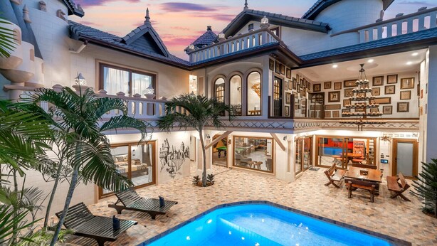 Une villa luxueuse dotée d’une piscine, d’un espace extérieur aménagé et d’un intérieur bien éclairé, agrémenté de tableaux encadrés.