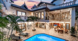 A luxurious villa with a swimming pool, outdoor seating, and a well-lit interior with framed pictures. - POTTERLAND Luxury Pool Villa Pattaya Walking Street  (Pattaya)