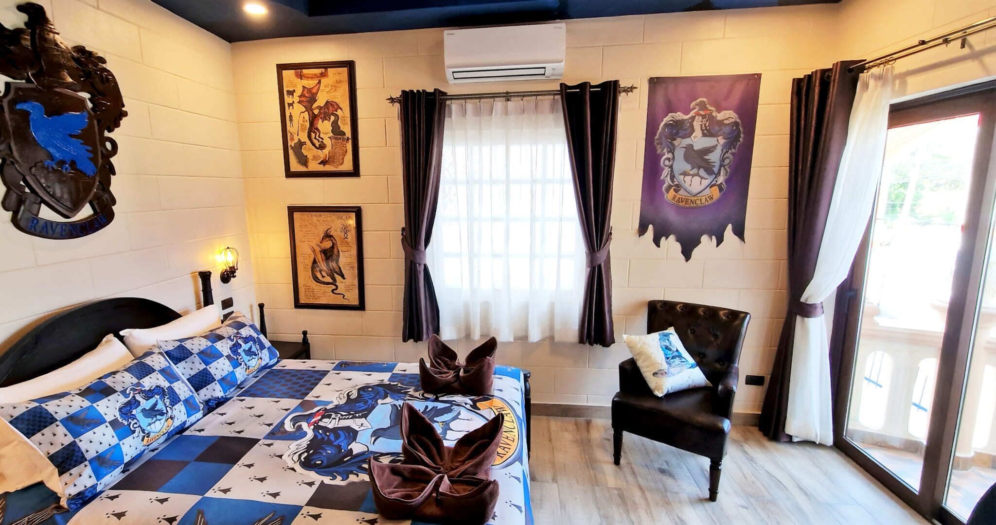 Une pièce avec une couvre-lit à carreaux, une chaise, une fenêtre avec des rideaux et des éléments de décoration murale, notamment un blason.