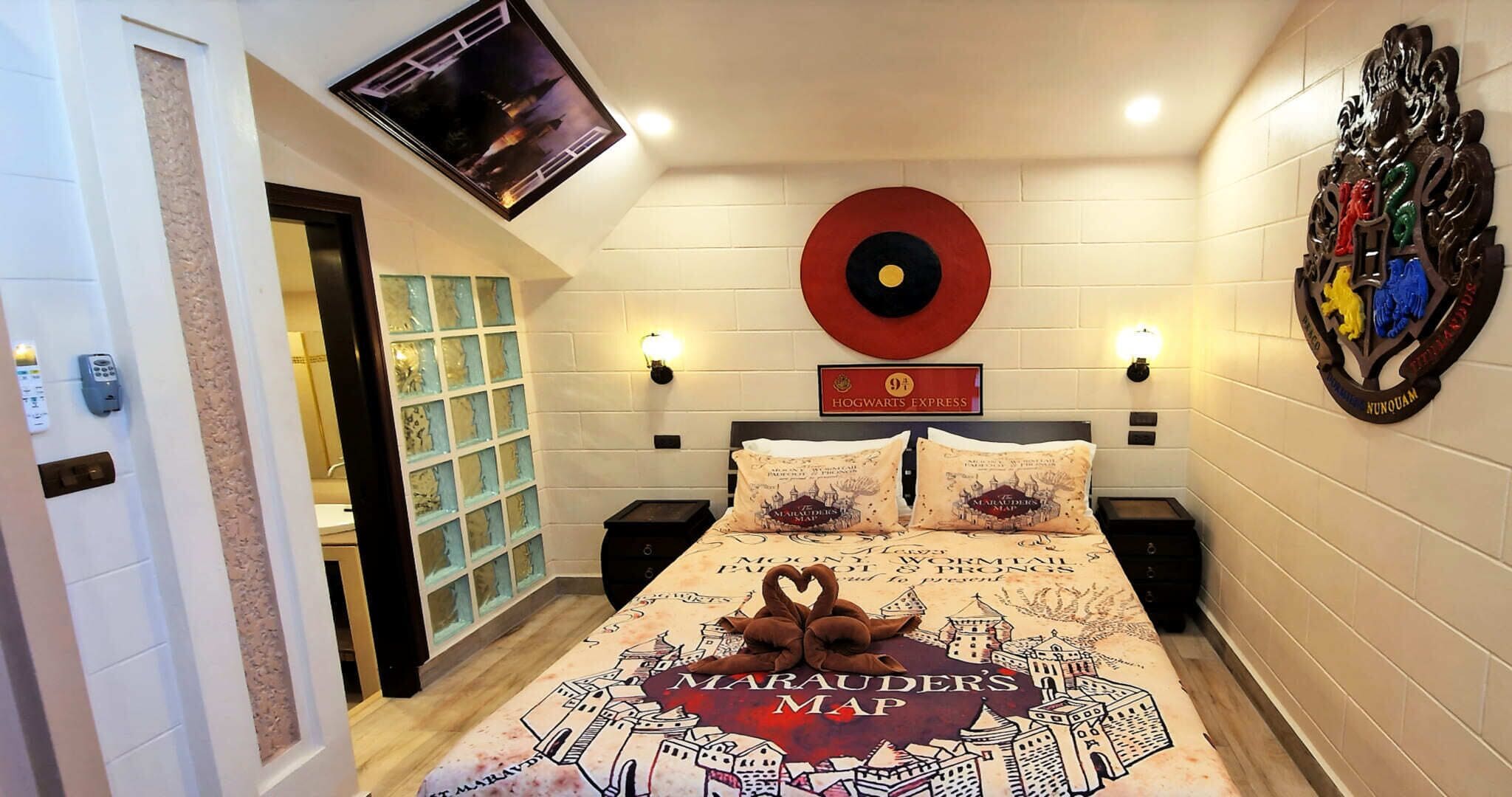 Ein Schlafzimmer mit einem Bett, das mit einem Design der wandernden Karte, einem Schild des Hogwarts-Expresses und einer rot-schwarz karierten, wandmontierten Dekoration versehen ist.