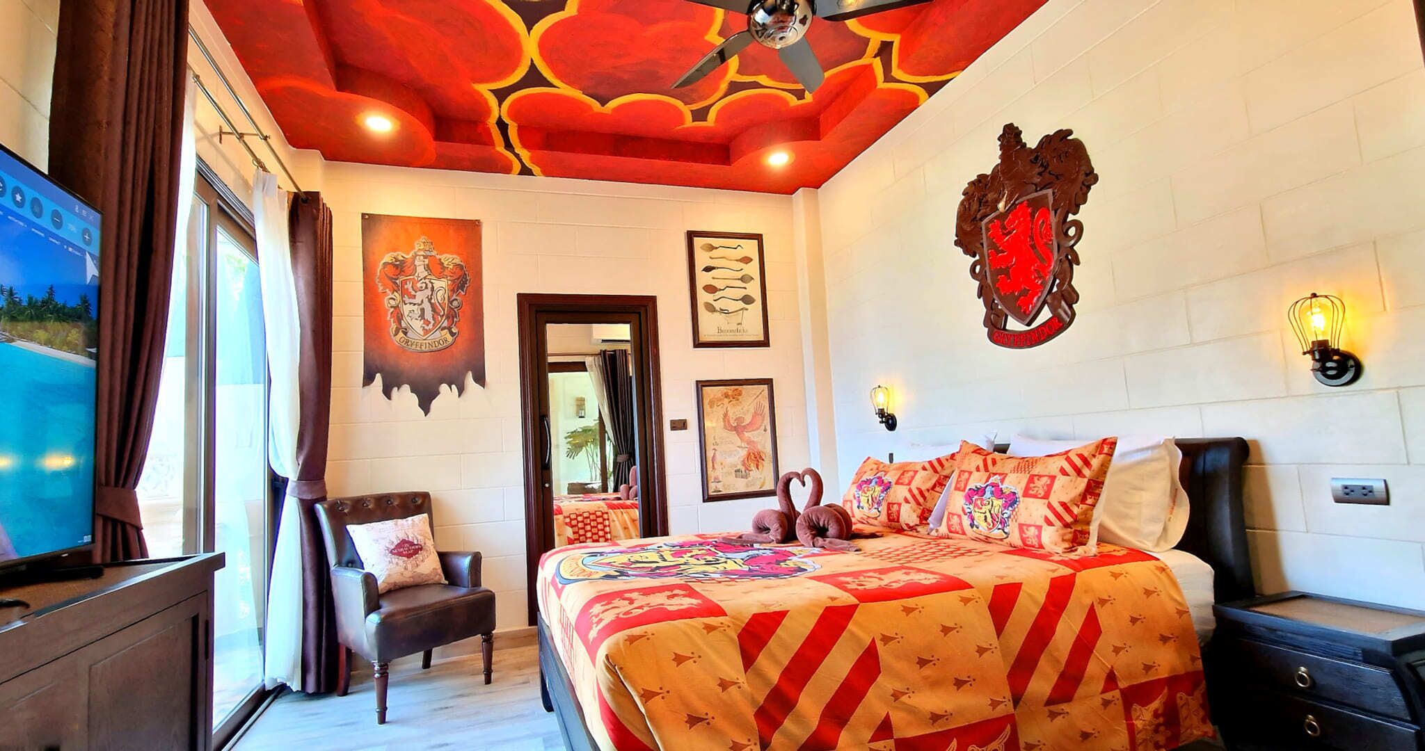 A bedroom with a large bed, a chair, a television, and a ceiling fan.