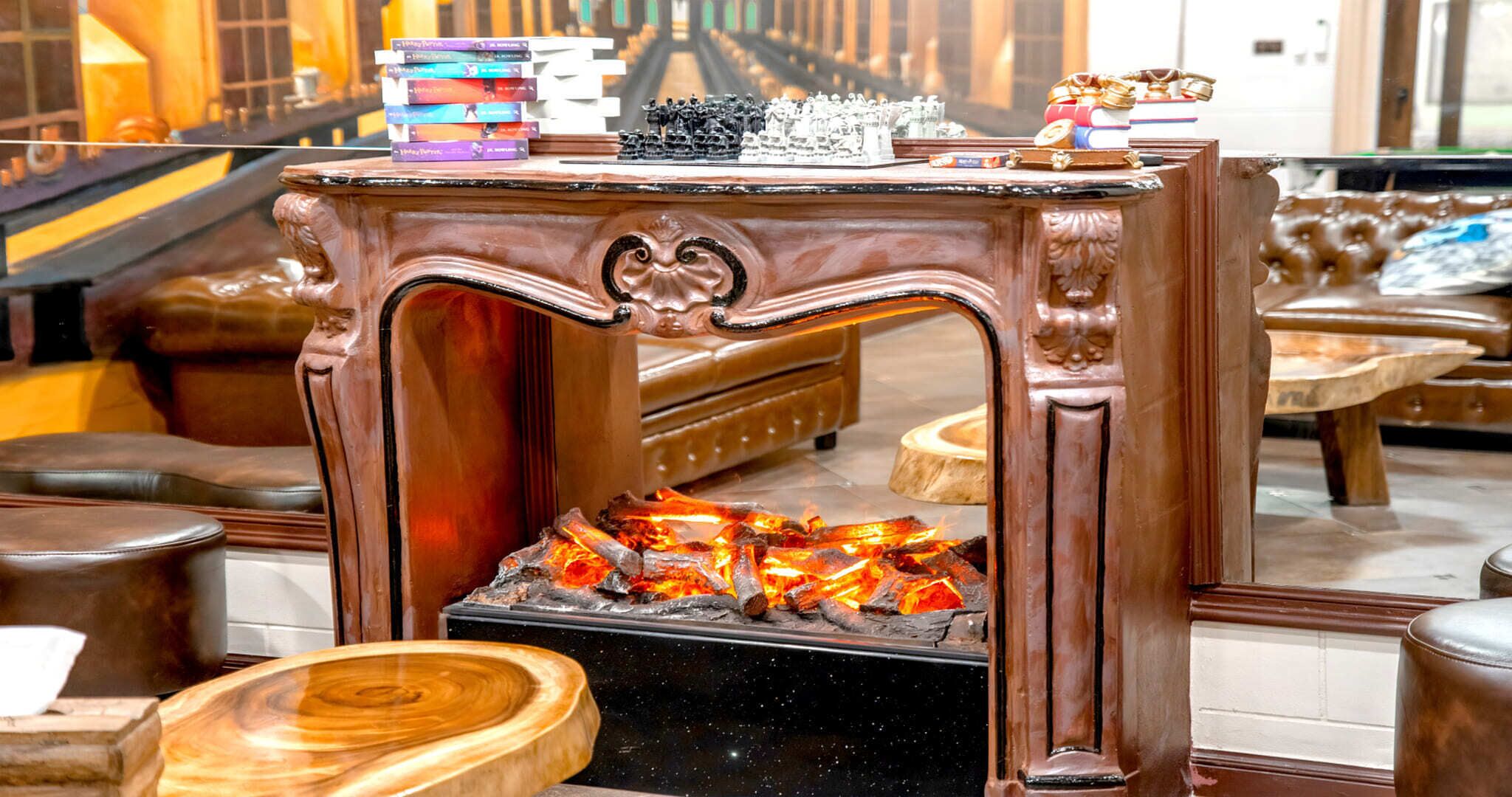 A wooden fireplace with a chessboard and books on top.