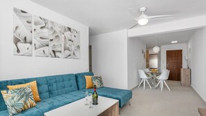 Ein modernes Wohnzimmer mit einem türkisfarbenen Sofa, einem weißen Couchtisch und abstrakten Wandbildern.