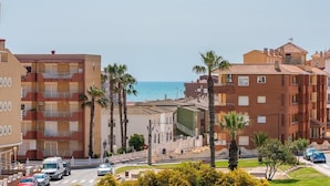 Ein Küstenwohngebiet mit mehrstöckigen Gebäuden, Palmen und freiem Blick auf das Meer.