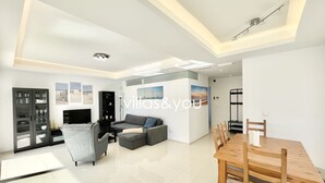 A modern living room with a sofa, TV, and dining area. - Allegra 19 Ciudad Quesada by Villas&You (Ciudad Quesada)