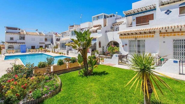 Un bâtiment blanc avec une piscine et un jardin.
