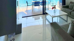 Een moderne woonkamer met een bank, een salontafel en uitzicht op een zwembad en terras.