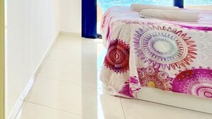 Een kamer met een bed, een groot raam en uitzicht op zee.