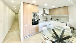 Una cucina moderna con tavolo da pranzo in vetro, mobili in legno ed elettrodomestici integrati.