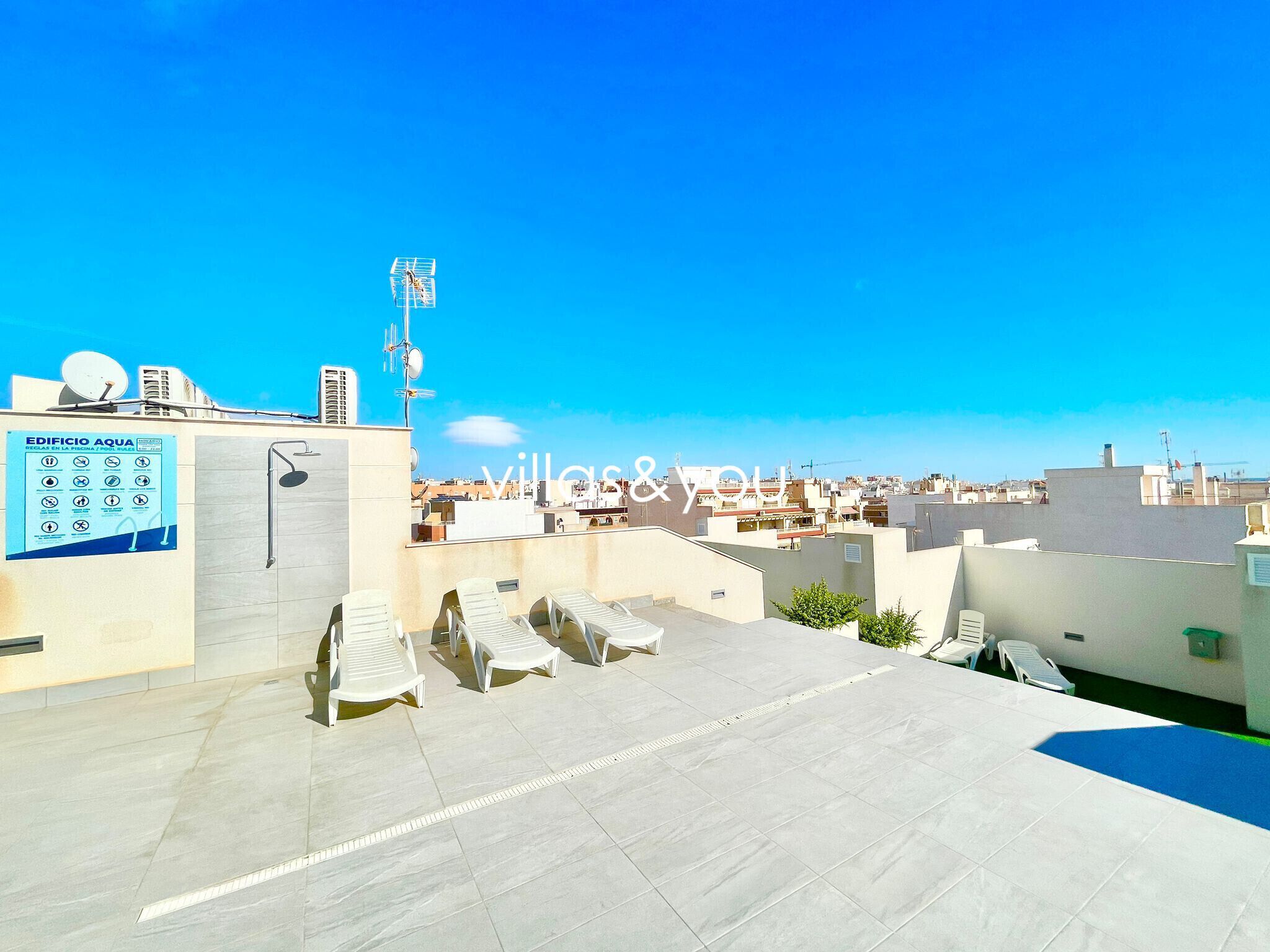 A rooftop terrace with lounge chairs, a pool, and a view of the cityscape.