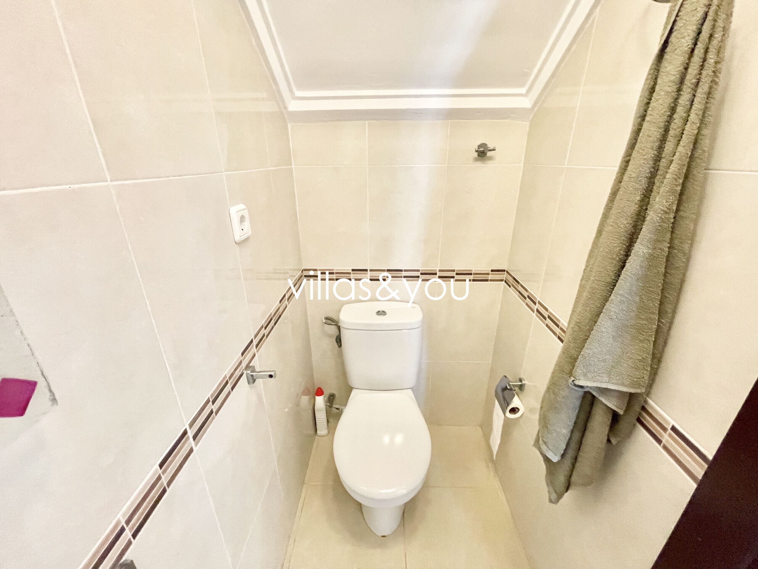 A compact bathroom with a toilet, a towel rack, and a hand dryer.