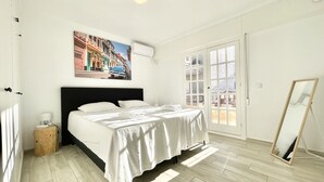 A bedroom with a bed, a painting, a mirror, and a door leading to a balcony. - Sunset Torrevieja by Villas&You (Torrevieja)