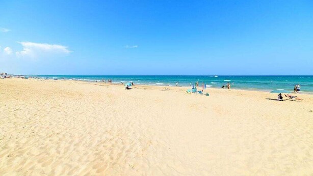 A wide sandy beach with clear blue water and a few people. - Sunset Torrevieja by Villas&You (Torrevieja)