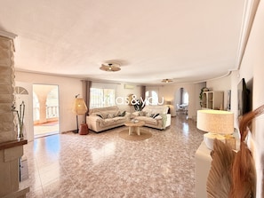 A spacious living area with a sofa set, a dining table, and a TV.
