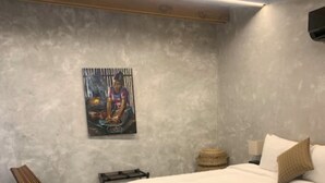 Un dormitorio con una cama, una silla, una mesita y un estante en la pared.