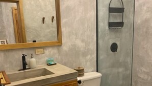 Un baño con tocador de madera, un espejo grande, un inodoro y una cabina de ducha de vidrio.