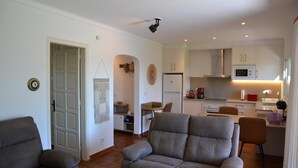 A modern living room with a grey sofa, a dining area with a table and chairs, and a kitchen with white cabinets and appliances. - Las Palmeras 5 - L'Estartit, Torre Gran (Estartit (L´))