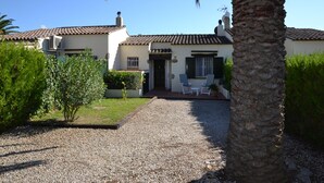 A two-story house with a gravel driveway leading to a front door. There are two outdoor chairs and a small table near the entrance. - Las Palmeras 5 - L'Estartit, Torre Gran (Estartit (L´))