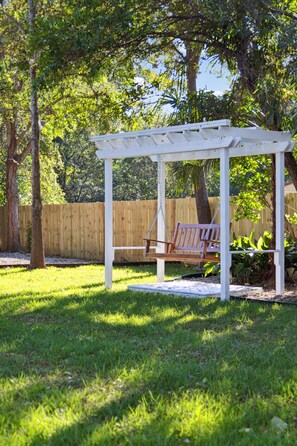 Relax in a serene outdoor space surrounded by lush greenery and a wooden fence.
