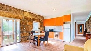Una cocina moderna con paredes de piedra, suelo de madera y armarios color naranja.