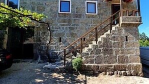 Un edificio de piedra con una escalera que lleva a una puerta, rodeado de vegetación.