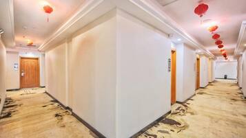 Un pasillo de hotel con piso alfombrado, paredes blancas y puertas a ambos lados.