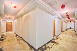 A hotel corridor with carpeted floors, white walls, and doors on both sides. - Junlan Hotel (Xiangyang)
