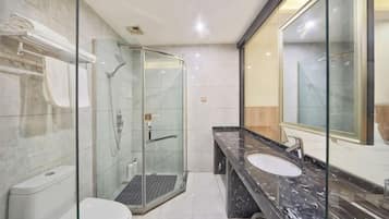 Une salle de bain moderne avec une douche à parois de verre, un lavabo en marbre et un grand miroir.