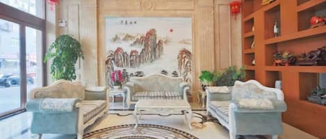 Un vestíbulo con un mural tradicional chino, dos sofás, una mesa de centro y una alfombra estampada.