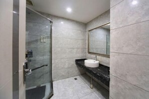 A modern bathroom with a glass shower enclosure, a white sink, and a marble countertop.