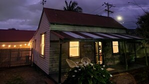 Une maison avec un toit en pente, une véranda et un petit jardin.