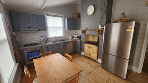 Une cuisine de taille réduite avec des meubles gris, une table en bois et un réfrigérateur en acier inoxydable.