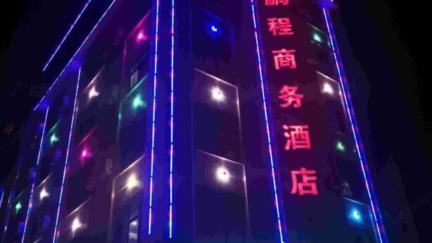 A building with vertical neon lights and a vertical sign with text.