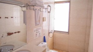 A bathroom with a sink, toilet, shower, and a window.