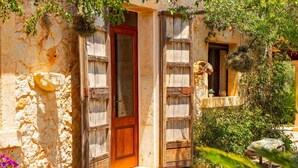 A rustic stone building with a wooden door and windows, surrounded by greenery and a stone bench. - Beautiful villa with pool in Llubí, in the center of Mallorca. (Llubí)